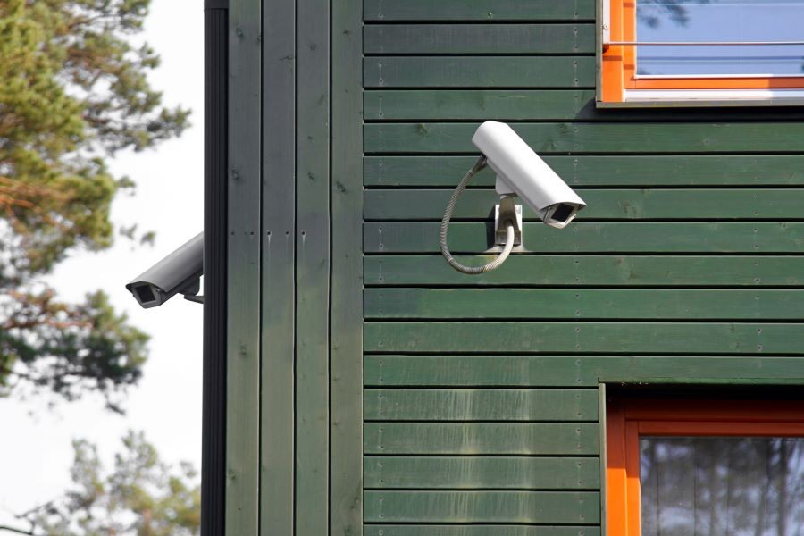 Two security cameras attached to a green home.