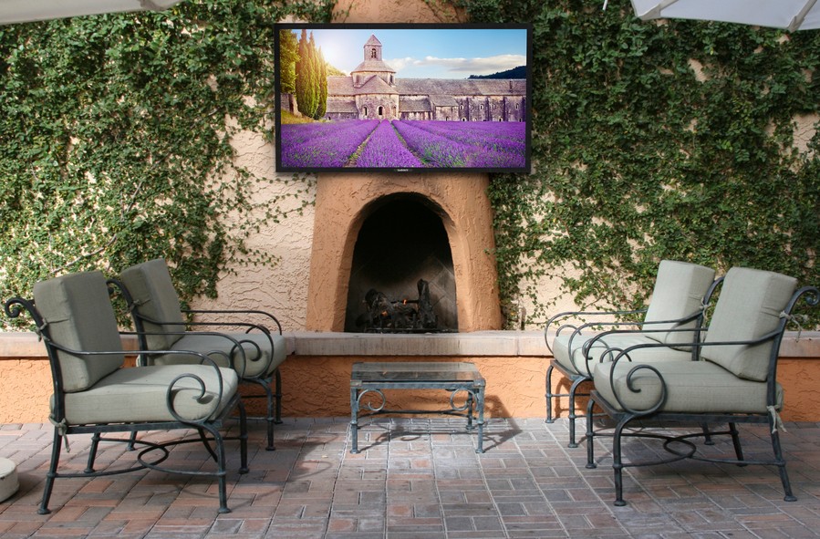 A SunBrite outdoor TV is pictures mounted over a Spanish-style fireplace on a McAllen patio.