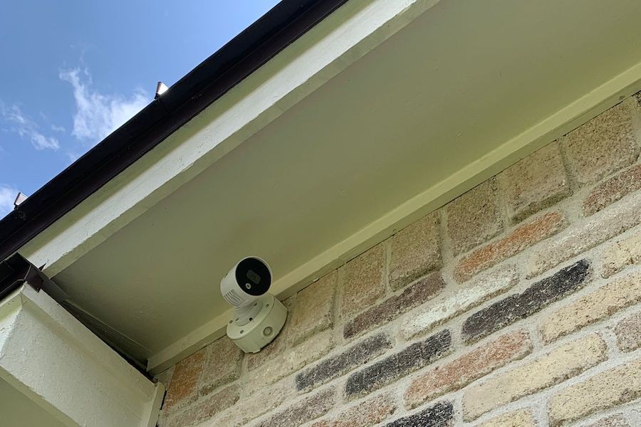  outdoor security camera system mounted on a brick wall beneath a roof overhang