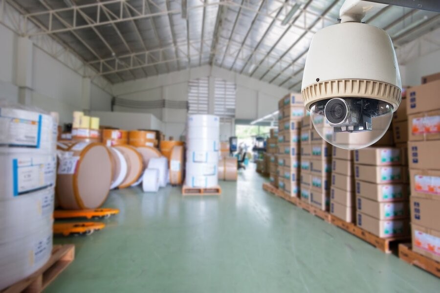 A warehouse with a smart security camera in the foreground in focus.