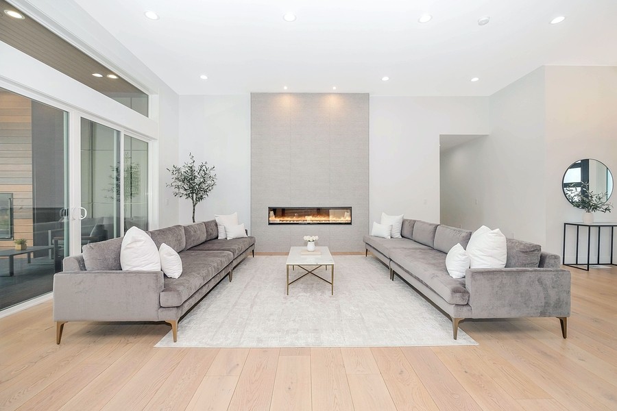 A living room with long couches, a fireplace, and in-ceiling speakers.