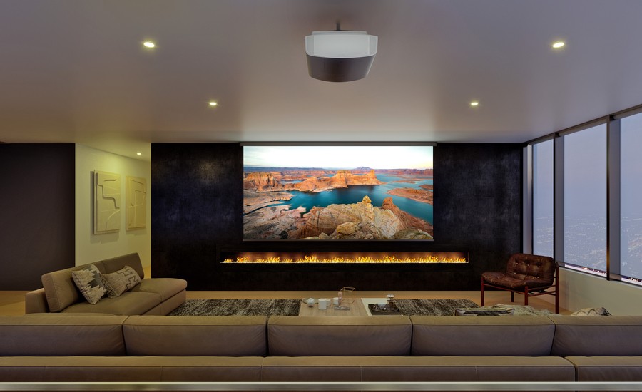 A modern, minimalistic home theater with sectional seating and a fireplace under the screen.